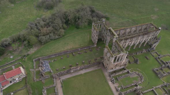 Aerial view birdseye orbit above the remains of North Yorkshire Rievaulx Abbey historical building r