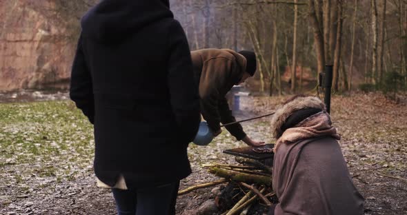 Camping, Three Campers Cook Sausages On A Fire.