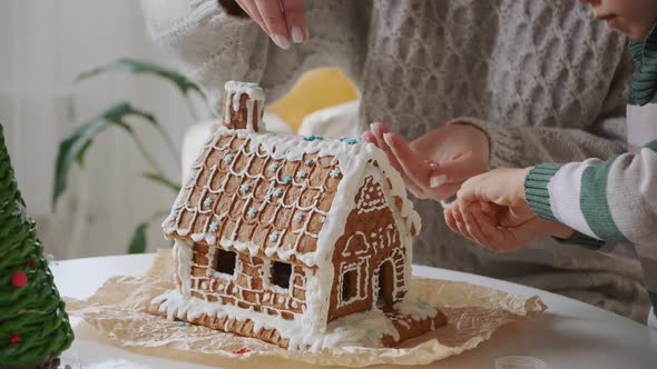 Little Boy with Mother Decorating Christmas Gingerbread House Together Family Activities and