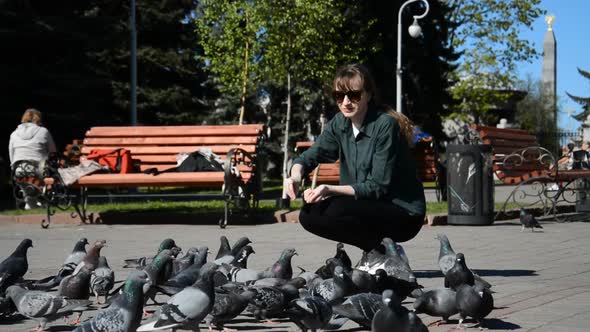 Beautiful Young Girl Student Feeding Pigeons in the Summer