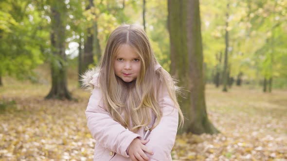 Cute Little Caucasian Girl Eats a Snack and Smiles at the Camera in a Park