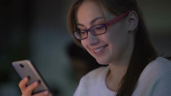 Young Woman Reading Texts on Smartphone, Smiling, Communicating With Friends