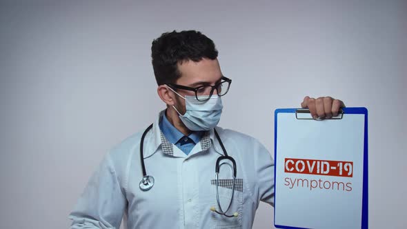 Male Doctor is Holding a Picture with the Inscription COVID 19 Symptoms Coronavirus Epidemic