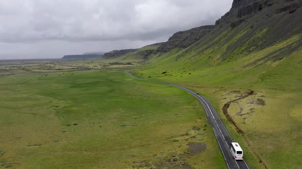 Tour bus driving through the mountains of Iceland with drone video following.