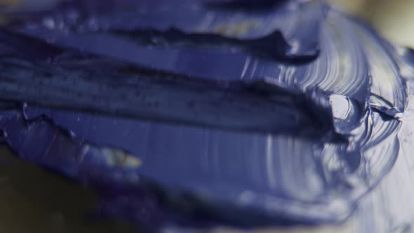 A macro image of artist's knife spreading and mixing paint colors.