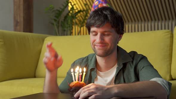 Young Man Celebrating Birthday Blows Out Candles on the Cake