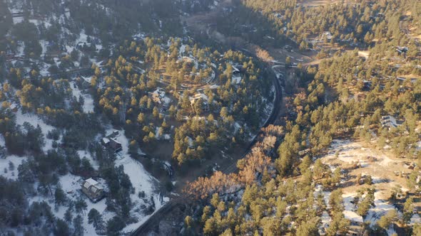 Aerial reveal forwards of Boulder Canyon Drive in Colorado during the winter as cars drive down road