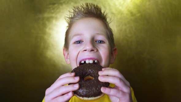 Happy kid eating a chocolate donut. Portrait of a boy with a face in chocolate