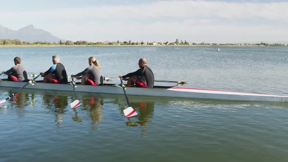 Four senior caucasian men and women rowing boat on a river