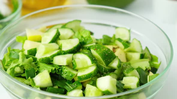 Woman Cooking Salad of Fresh Green Vegetables and Herbs