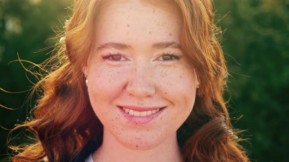 Attractive Woman with Curly Hair Smiles to Camera on Street