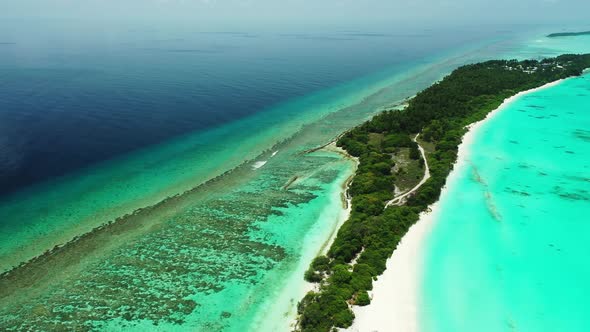 Wide above travel shot of a sandy white paradise beach and aqua blue water background in colorful 4K