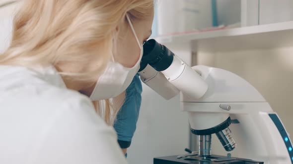 Scientist Microbiologist Examines Biological Blood Samples Under a Microscope. Female Researcher