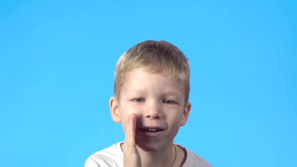 Child Telling Secret Covering Mouth with Palm, Looking at Camera.