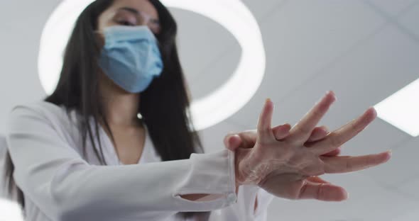 Woman wearing face mask sanitizing her hands at office