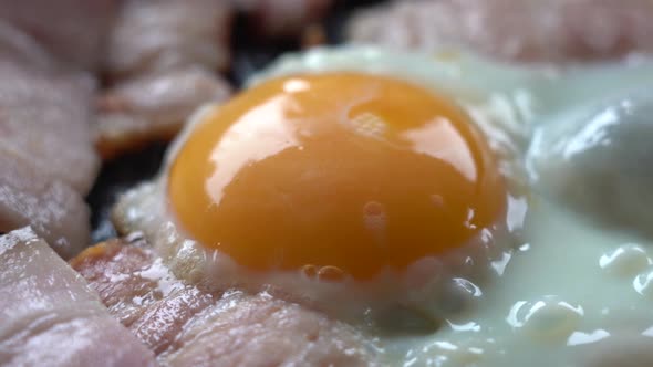 EGG and BACON Are COOKED in a Frying Pan. Pieces of Bacon and Eggs in a Hot Frying Pan, Close-up