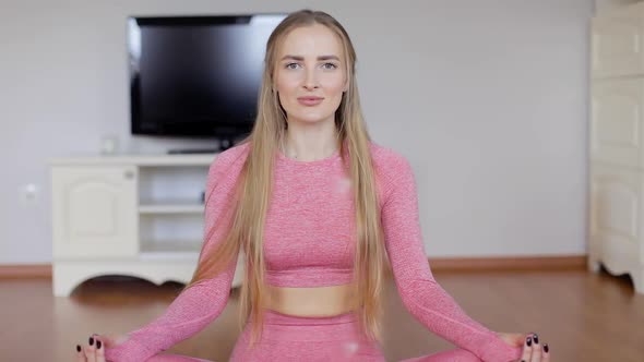 Pretty and happy woman sitting on fitness mat in butterfly pose.