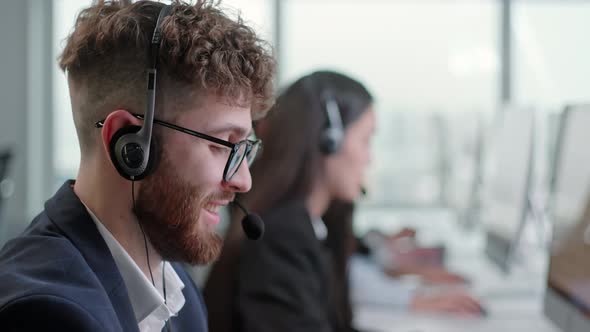 Close Up Portrait of a Technical Customer Support Specialist Talking on a Headset While Working on a