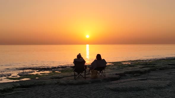 People sit on the beach and watch the sunset 4 K