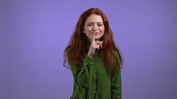 Smiling Woman Holding Finger on Her Lips Over Violet Background