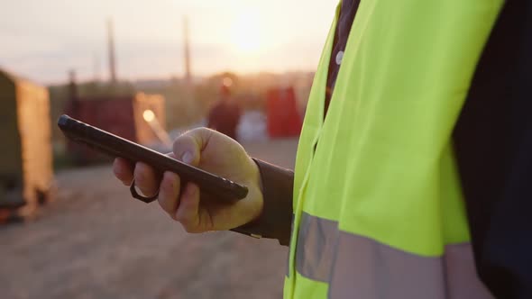 Builder Holds His Black Smartphone in His Hand