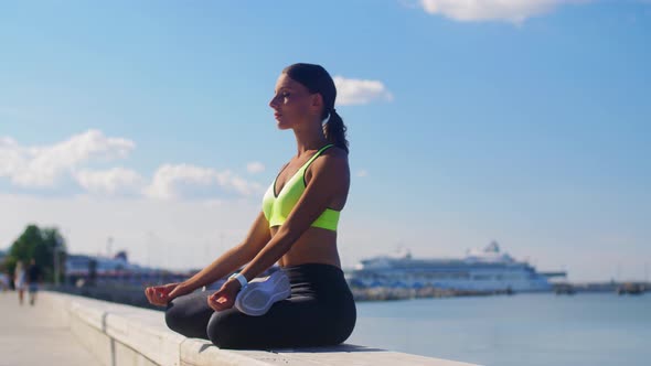 Young Woman Meditating in Lotus Pose at Seaside