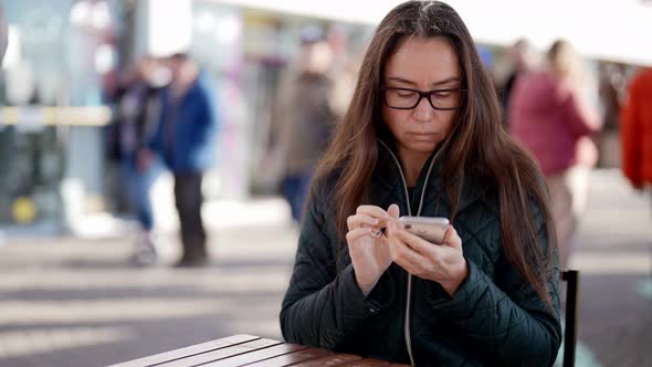 A Closeup Portrait of an Adult Woman with Glasses Sitting at a Table in an Outdoor Cafe Writing a