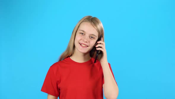 Little Female Talking on the Phone at Blue Background