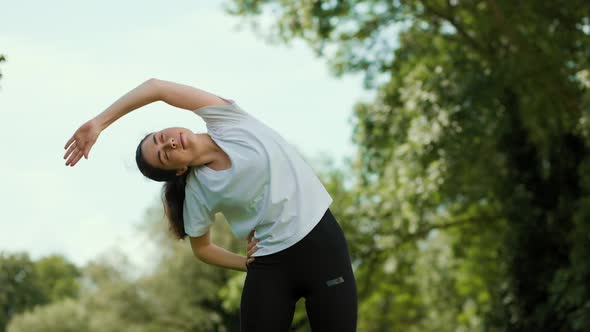 A young fit woman in sports clothes doing body bents. Real time. The concept of wellness.