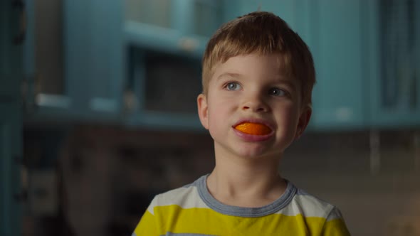 Preschool Blonde Boy Playing with Orange Peels in His Mouth. Smiling Kid with Orange Fruit in Mouth