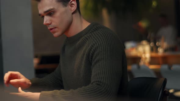 Happy man wearing sweater working on laptop