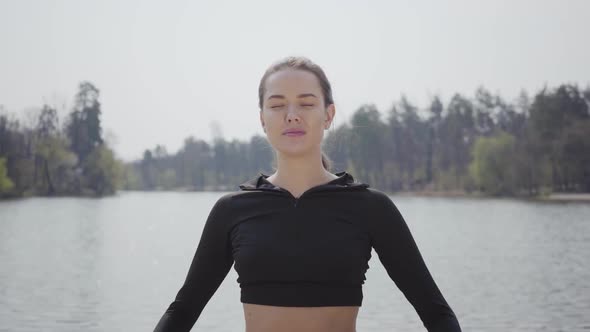Attractive Slim Girl Doing Sport Exercises, Standing on the Riverbank. Beautiful Landscape in the