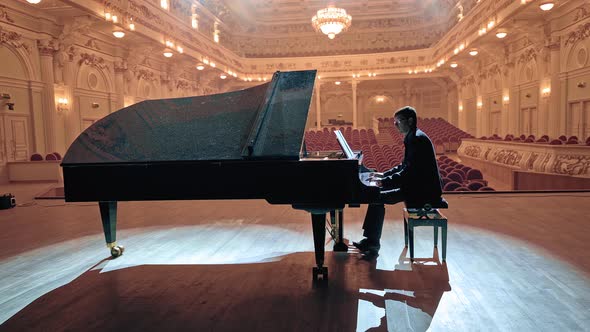 Pianist in Dark Suit Playing on a Grand Piano on Big Stage in Concert Hall