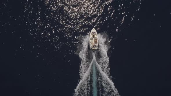 Aerial view of small speed boat with trailing wake on sea.