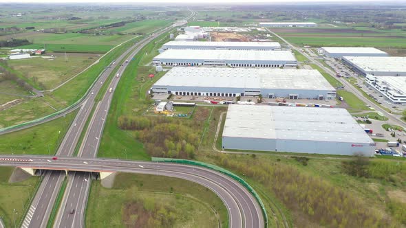 Aerial Shot of Industrial Warehouse Storage Building Loading Area where Many Trucks Are Loading Unlo