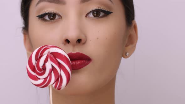 Fashion Portrait of Asian Woman with Lollipop in Studio