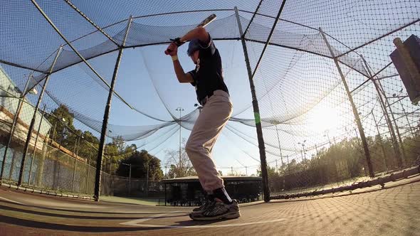 A baseball player practicing at the batting cages.