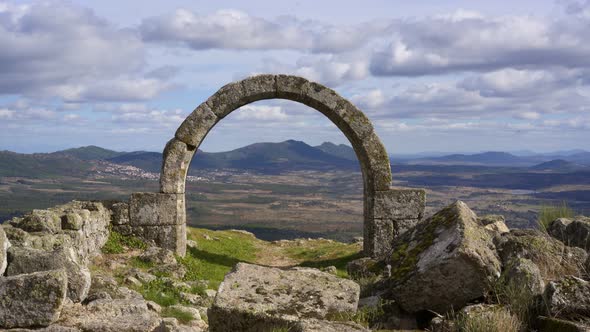 Stone arch ruins of an old chapel with mountains in the background in Monsanto, Portugal