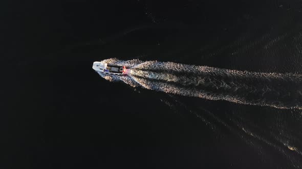 Aerial top down view of a boat at sea in Scotland with beautiful water at sun