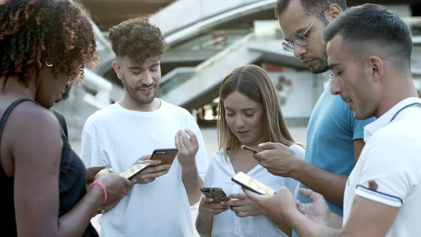 Cheerful Friends Standing in Circle on Square with Phones