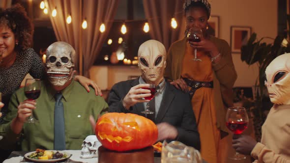 Masked Friends Drinking and Dancing at Halloween Dinner Party