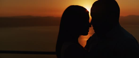 Close up of a young couple embracing at sunset, spending a romantic evening together. Slow motion  