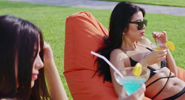 Two Women in Biking Drinking Cocktail and Sunbathing Outdoors