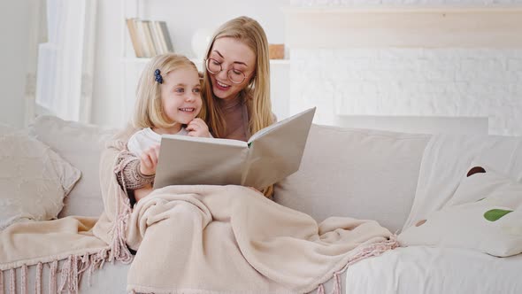 Smart Adult Mother Babysitter Reading Book Literature Fairy Tale to Little Daughter Schoolgirl