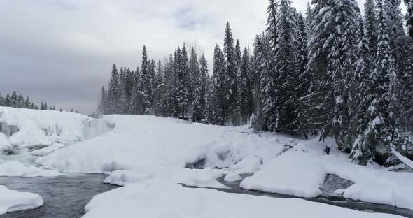 Stream flowing through snowy forest 4k