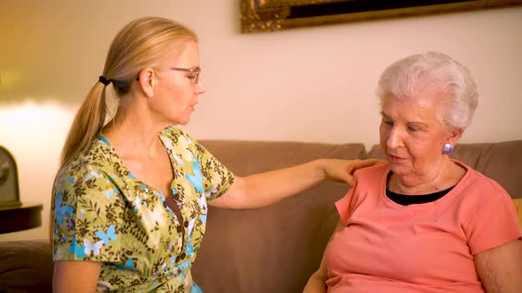 Closeup of home healthcare nurse helping massage elderly woman’s shoulder.