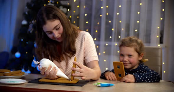 Woman and Little Girl Decorate Gingerbread House