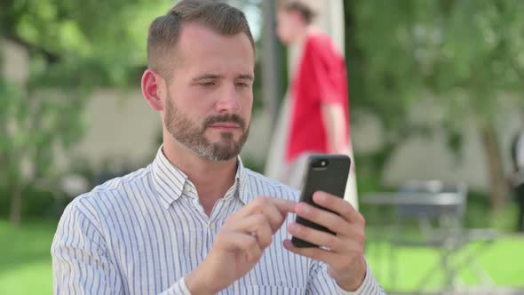 Outdoor Portrait of Middle Aged Man Browsing Internet on Smartphone