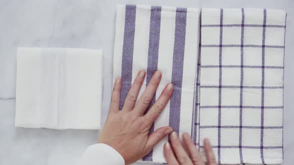 Folding black and white patterned paper towels on marble surface.