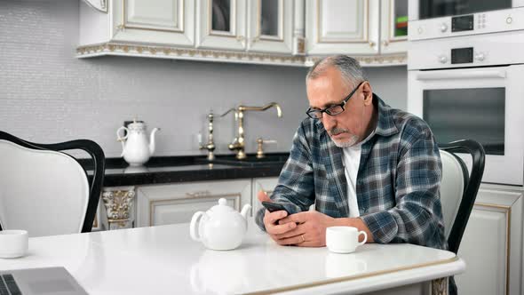 Pensive Senior Person Texting Looking at Screen of Telephone Drinking Tea at Cuisine